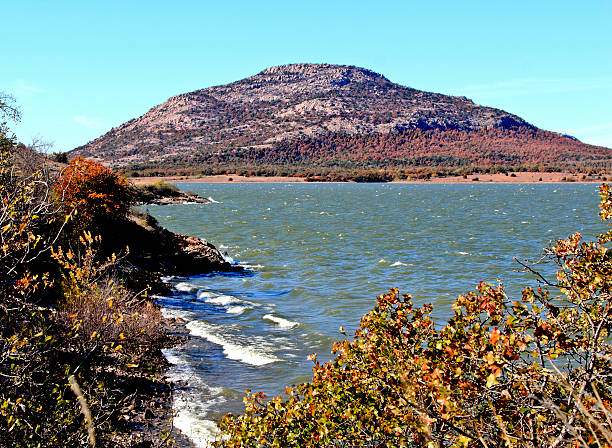 Mount Scott with Lake Lawtonka in the foreground. Fall foliage is seen and there are large waves due to high winds. Mount Scott which is named after General Winfield Scott is located in the Wichita National Wildlife Refuge near Lawton, OK and the Fort Sill Military Base.